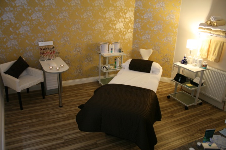 The beauty room: a treatment couch against gold damask wallpaper, with a manicure table by the window