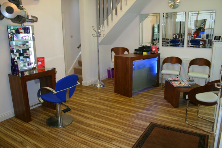 Inside Seventh Avenue: a royal blue chair at a mirror, the blue-lit reception desk and the stairs up to the beauty room